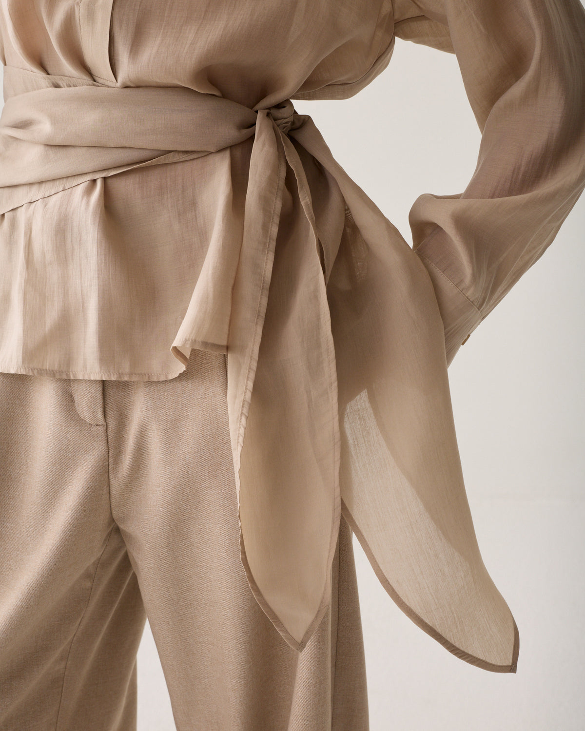 Close-up of Summum wrap waist tie detail top with long sleeves