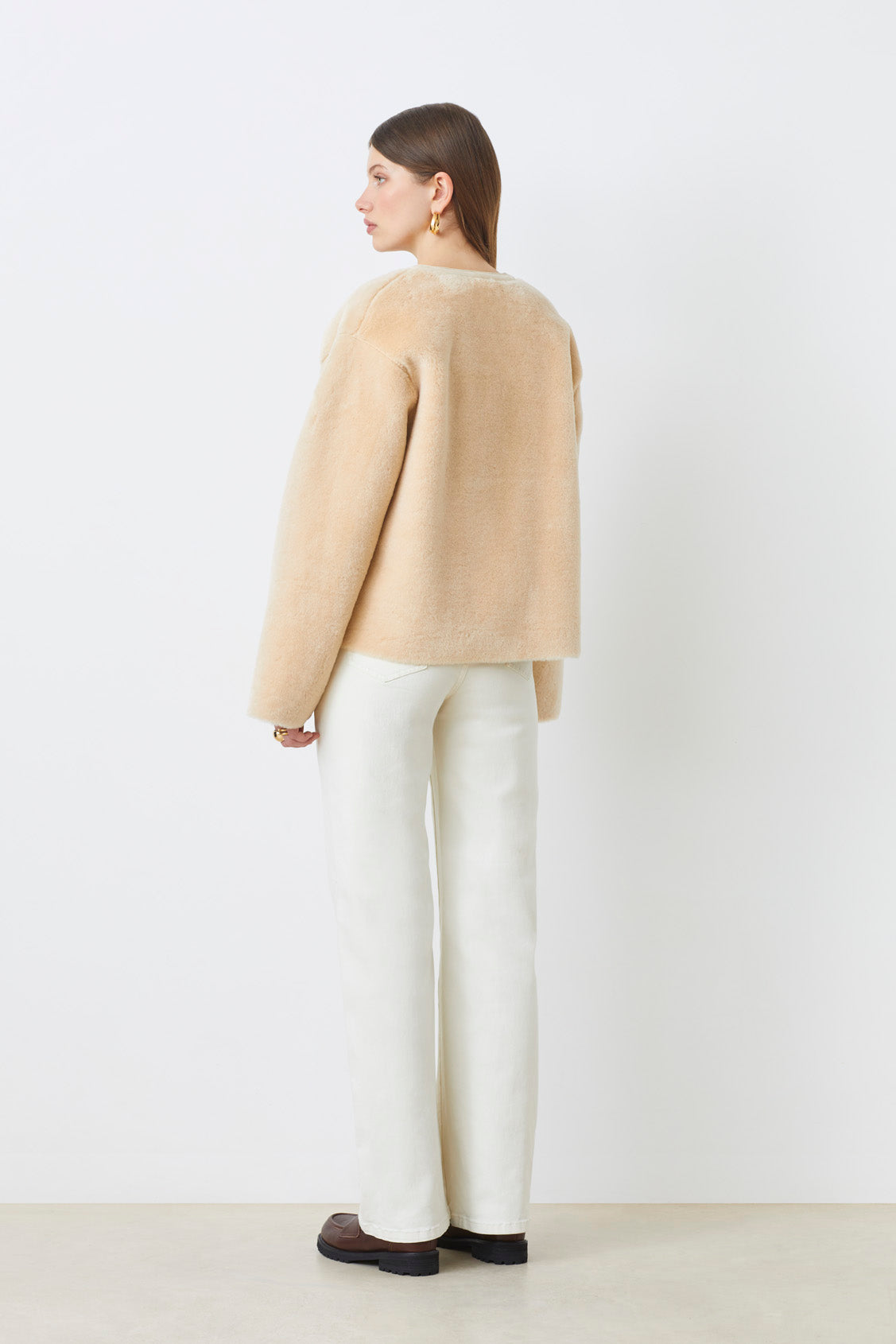Back view of loose fit cream jacket by Suncoo layered over neutral outfit
