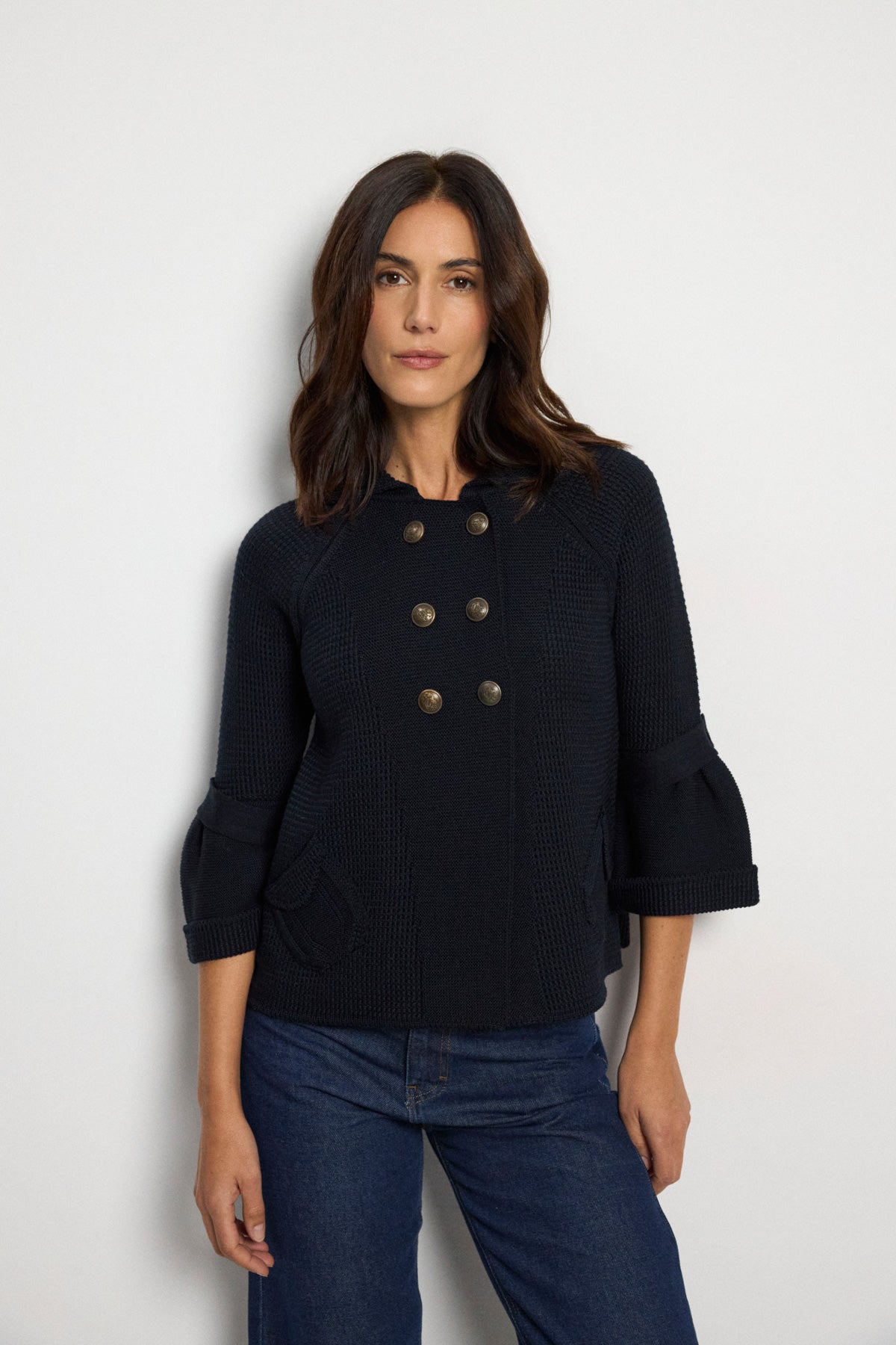 Tinta Pacifica navy double-breasted knitted jacket with metallic buttons, flared sleeves, collar and flap pockets – front model view.