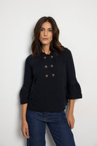 Tinta Pacifica navy double-breasted knitted jacket with metallic buttons, flared sleeves, collar and flap pockets – front model view.