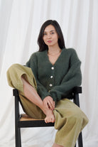 Twins Malia forest green button-front cardigan shown in a seated front view