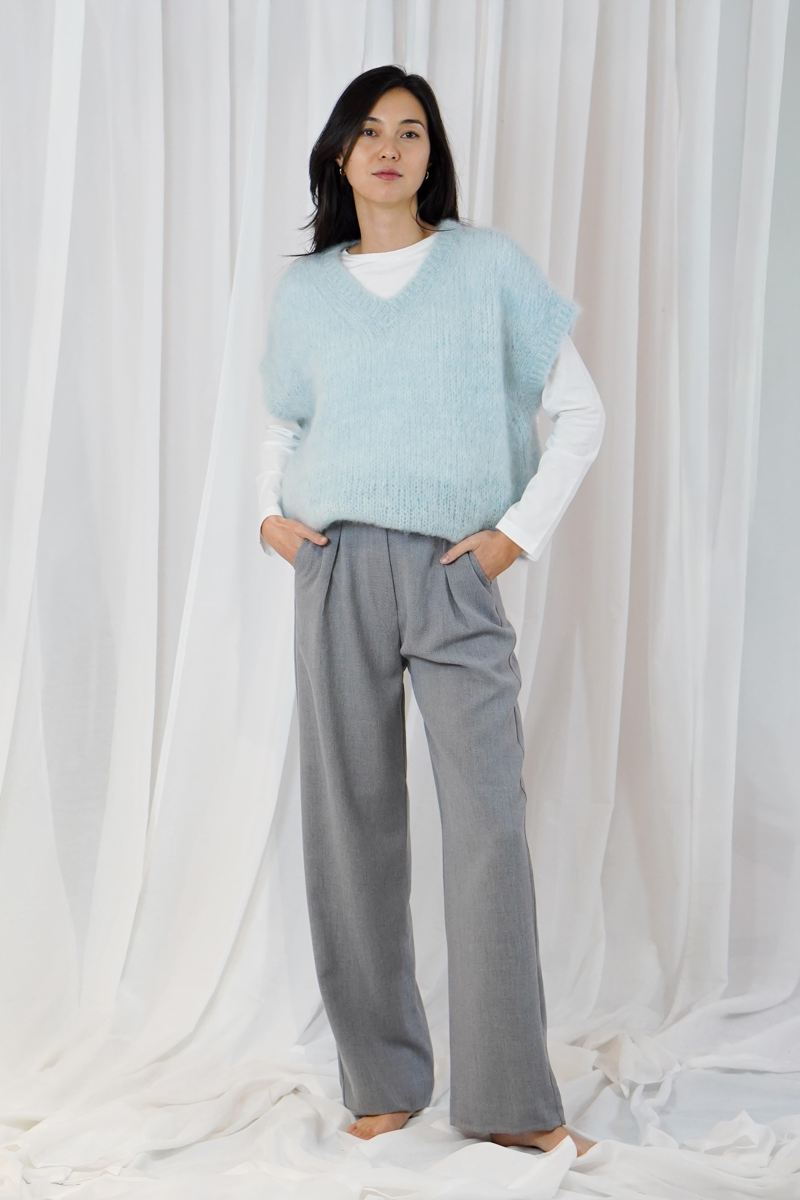 Twins Queens white crew neck long sleeve T-shirt layered under a blue knitted vest