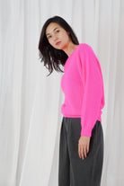 Twins Sanibel neon pink relaxed boat neck jumper worn with black trousers