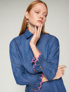 Close-up of pink scalloped cuff embroidery on Vilagallo denim shirt