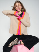 Model wearing Vilagallo beige wool cardigan with vibrant pink and orange edging