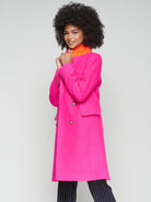Women’s tailored fuchsia coat with orange undercollar and lapel collar.