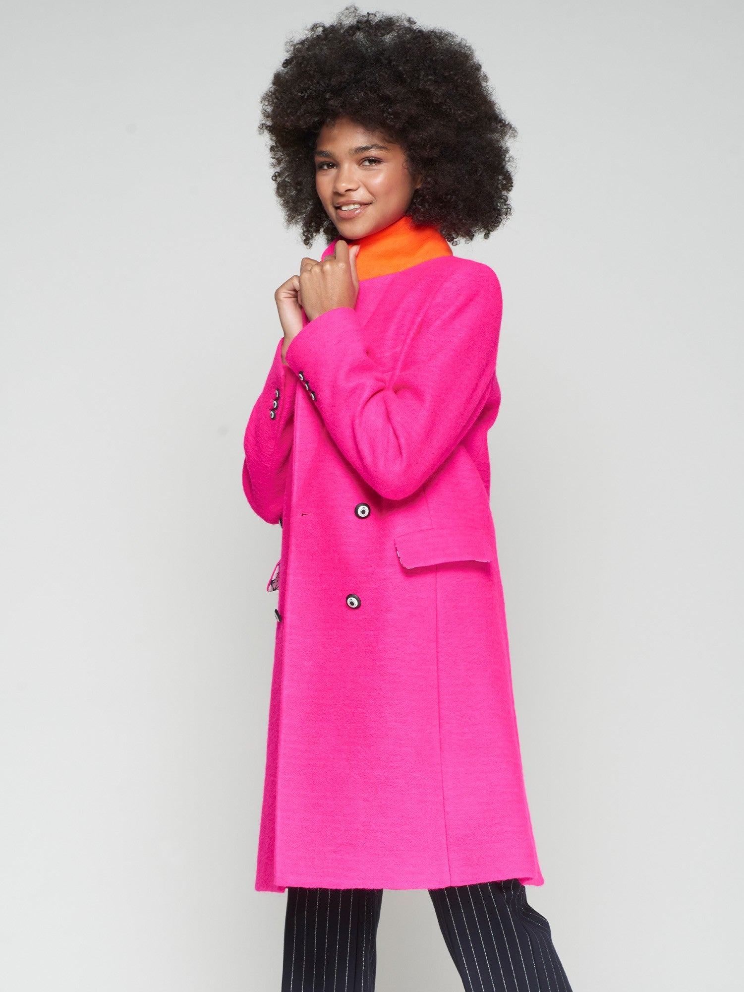 Women’s tailored fuchsia coat with orange undercollar and lapel collar.